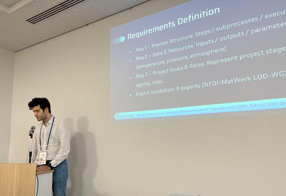 Ebrahim standing next to the presentation screen showing a slide from his presentation