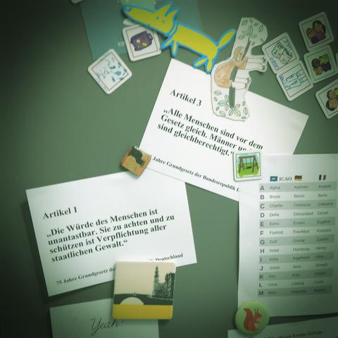 Foto einer Kühlschranktür mit vielen Magneten unter anderem in Tierform, dazwischen Zettel. Die zwei prominentesten zeigen jeweils Artikel 1und Artikel 3 des Grundgesetzes der Bundesrepublik Deutschland. Sie lauten: "Artikel 1: Die würde des Menschen ist unantastbar. Sie zu wahren und zu schützen ist Verpflichtung aller staatlicher Gewalt." sowie "Artikel 3: Alle Menschen sind vor dem Gesetz gleich. Männer und Frauen sind gleichberechtigt."
