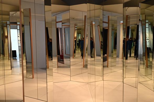 Viele raumhohe im 60 Grad Winkel aufgestellte Spiegel ergeben eine unendliche Raumwirkung