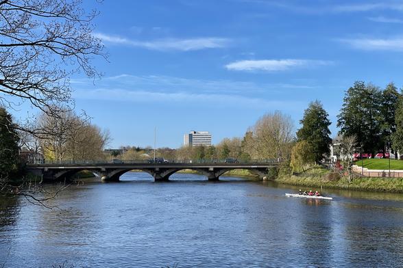 Rowers on river near bridge