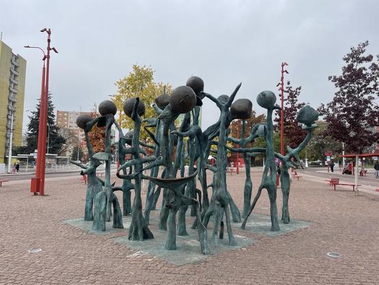 Commemorative statue of Mendel with peas lifted up by arms of footed figures