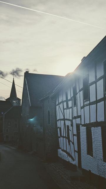 old house with colombages in Fourons, sunset and church tower in the background