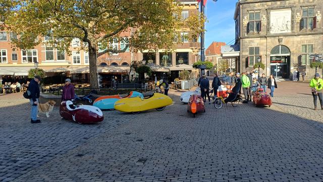Het bonte gezelschap verzameld bij een boom in herfstdracht op de Markt in Gouda