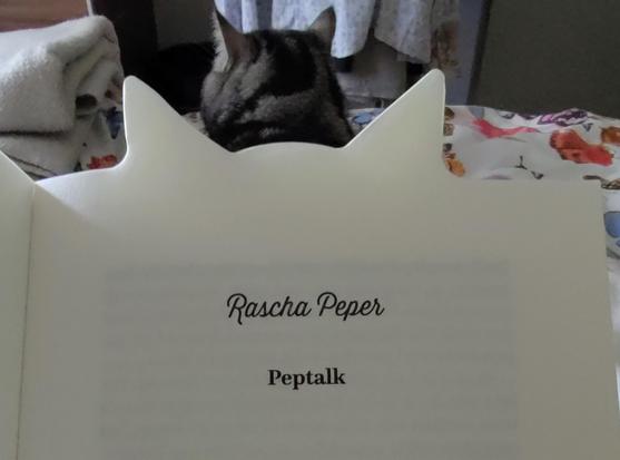 Hier is het boek opengeslagen bij het verhaaltje Peptalk van Rascha Peper. Achter de oortjes die boven het boek uitsteken ligt katje Maddy met haar oortjes omhoog