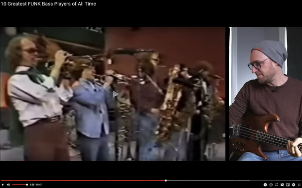 Screenshot eines Youtube-Videos von Scott's Bass Lessons. Rechts ist Scott, ein weißer Mann mit Bass und grauer Mütze auf dem Kopf, er trägt eine Brille und guckt sich ein Video von Tower of Power an.
In der linken Hälfte (ca. 70% des gesamten Bildes) ist die Band zu sehen. Ganz links steht ein Trompeter mit Sonnbrille, Schnurrbart und mittellangen Haaren. Er ist nach hinten geneigt.