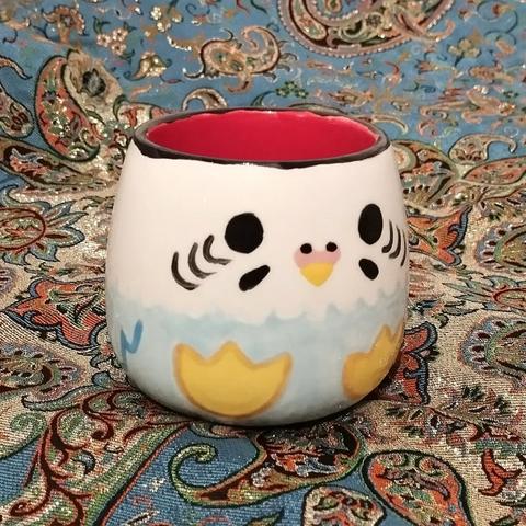 Photo de la même tasse mais de trois quart. On voit l'intérieur de la tasse, qui est rouge.