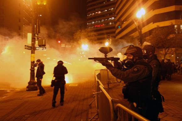 Image of cops in riot gear, firing tear gas at protesters, at 14th and Broadway, in Oakland, on October 25, 2011.
