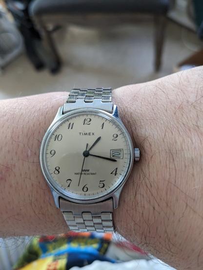 An old wind-up Timex wristwatch on my wrist, with a date complication.