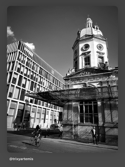 Black and white photo of outside of Smithfield market with a cyclist in the forefront.