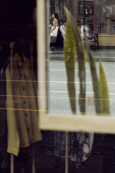 A mirror in a storefront reflects a cafe street scene.