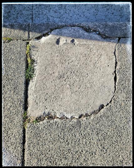 This image shows acrack in the sidewalk that closely resembles a (not so) scary ghost.