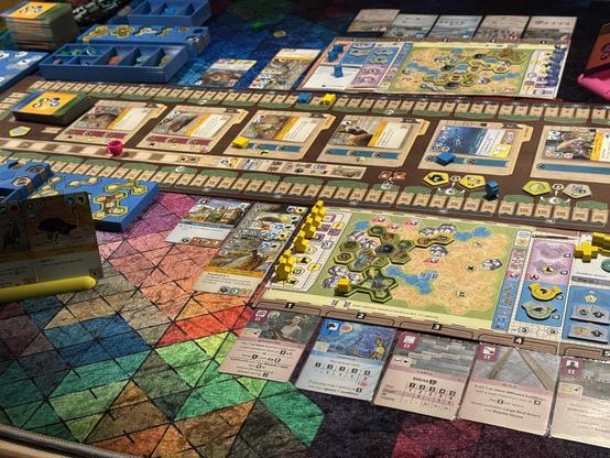 The Ark Nova board game on the table on a colourful table cloth.