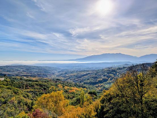 View of autumnal woods and fog over the Pescara River valley with the Maiella massif in the background, seen from the Voltigno plateau, on the Gran Sasso massif, in Abruzzo (Italy)
