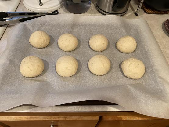 eight dough balls on parchment paper on a baking sheet