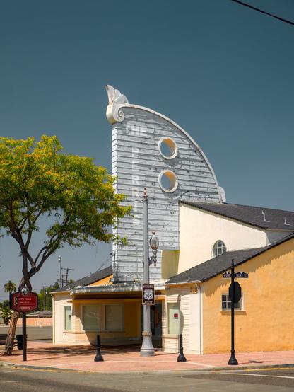 The tower of a long closed, disused theater building that faintly reads "Perris"