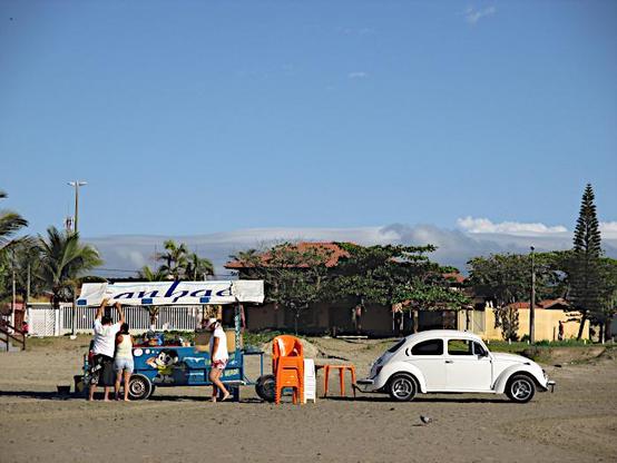 Foto van Volkswagen kever op strand bij een stalletje voor verkoop