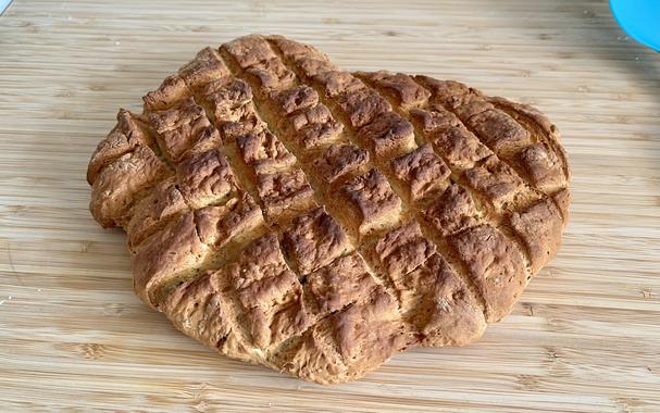 an irregular piece of flat bread, the top of which is cooked quite dark, and has been scored in a criss-cross pattern before baking
