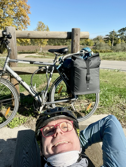 Ich liege auf einer Bank und im Hintergrund steht mein Fahrrad mit Packtaschen