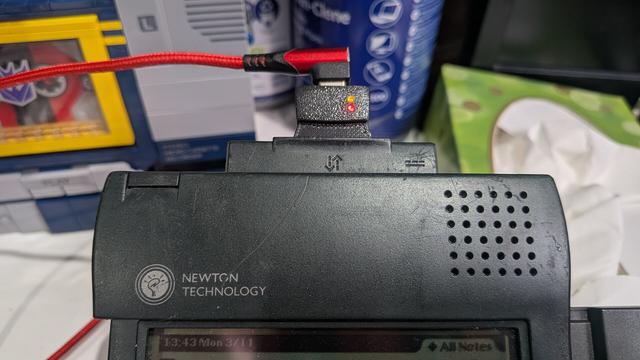 The top tired of a personal digital organiser, with a red cable connected into it