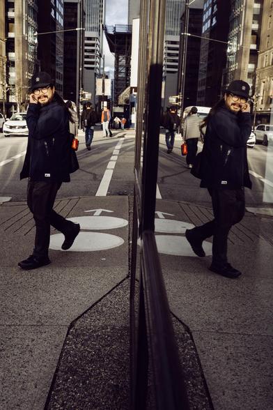 A man and his reflection glance at the photographer at an intersection.