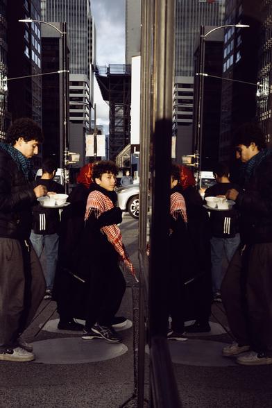 A woman glances at the photographer amidst a collection of people on a busy street.