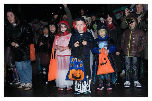 A hoard of kids in costumes defy the rain carrying bags of treats.