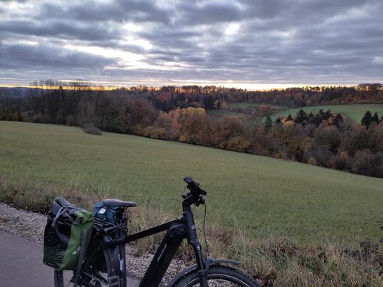 Fahrrad steht auf einer Straße, im Hintergrund das erste gelb des Sonnenaufgangs