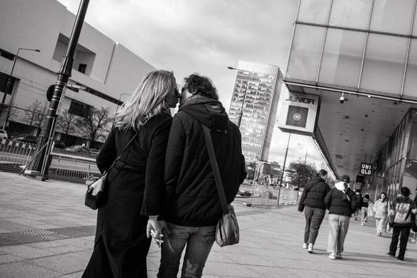 A couple kiss tenderly as they walk down a Warsaw street