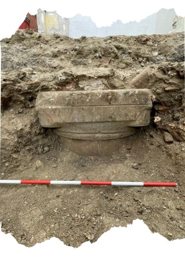 Fondazione circolare di pietra scoperta durante gli scavi archeologici a Camerino, con una striscia di misurazione in primo piano.