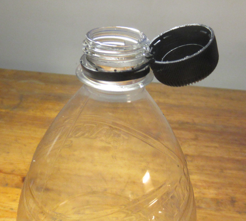 Muovisen juomapullon yläosa, jossa avattu ja sivulle käännetty korkki pysyy irtoamatta.