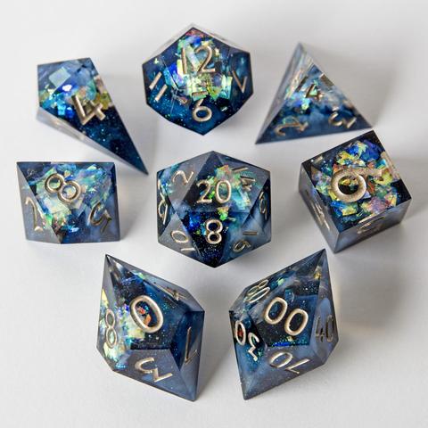 Ein klassisches 8-teiliges TTRPG-Würfelset in tiefem Blau mit Glitzer und weißen Wirbeln im Inneren.

Auf dem Bild liegen alle Würfel mit der höchsten Seite nach oben und sind um den D20 herum angeordnet. 

Das Set besteht aus D4 Shard, D4 Pyramide, D6, D8, D10, D00, D12 und D20. Die Nummern sind in einem Tinplate bemalt.