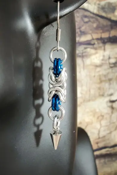 Boucles d'oreilles en maille, comportant des anneaux bleu paon et un pendentif en forme de pique.