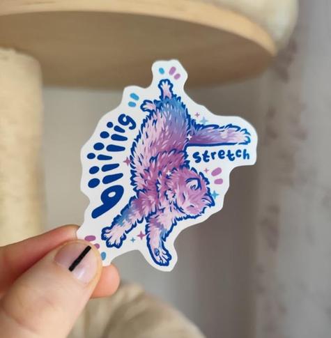 hand holding up a sticker of a kitty stretching titled "biiiig stretch"