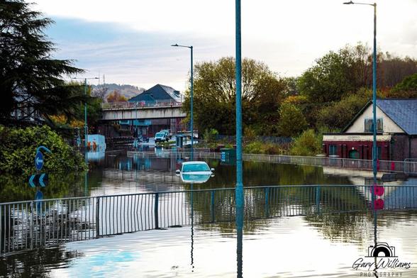 Vehicles almost completely covered by floodwater at Cwmbwrla roundabout in Swansea, with The Gatehouse pub located just above the junction on Carmarthen Road.