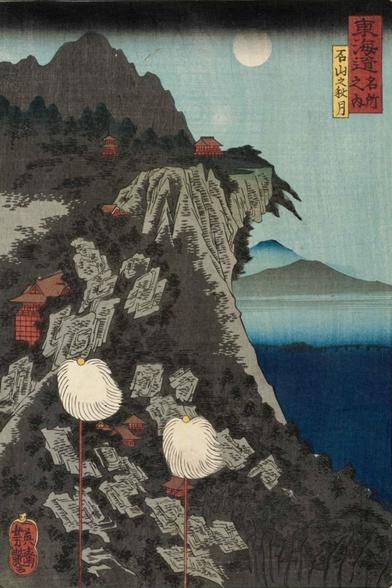 A full moon high in the sky beyond a cliff looking over water towards mountains in the distance.