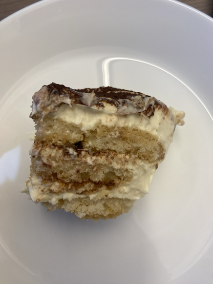 A piece of tiramisu on a white plate.