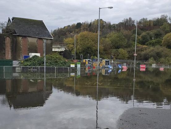 View from the Cwmbwrla side of the railway bridge showing Cwmbwrla roundabout under floodwater with pumping equipment in the distance.