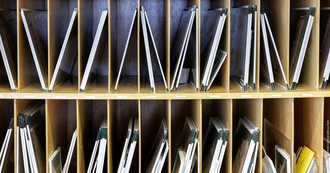 Holzregal mit mehreren Fächern, die mit rechteckigen Schutzrahmen gefüllt sind für die Aufbewahrung empfindlicher Papiere oder Dokumente.