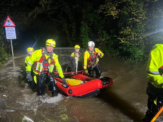Emergency crews in inflatable boats rescuing dogs from floodwaters at Glanrhyd Dog Sanctuary, Carmarthenshire.