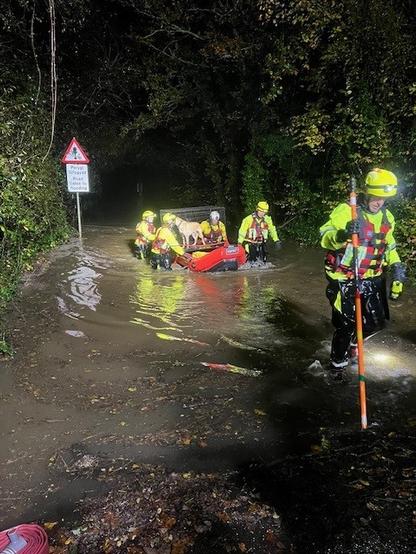 Rescue workers with inflatable boats and dogs during the flooding response at Glanrhyd Dog Sanctuary.
