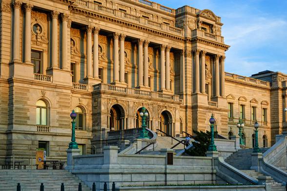 Thomas Jefferson Building facade with golden light on ornate Beaux-Arts columns and green lamp posts.