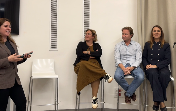 A panel of three founders listens as the moderator asks a question