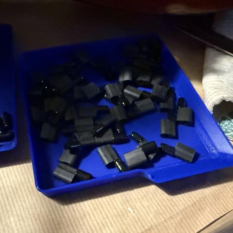 Photo of a blue parts tray with lots of tiny plastic pins with rubber sleeves attached.
