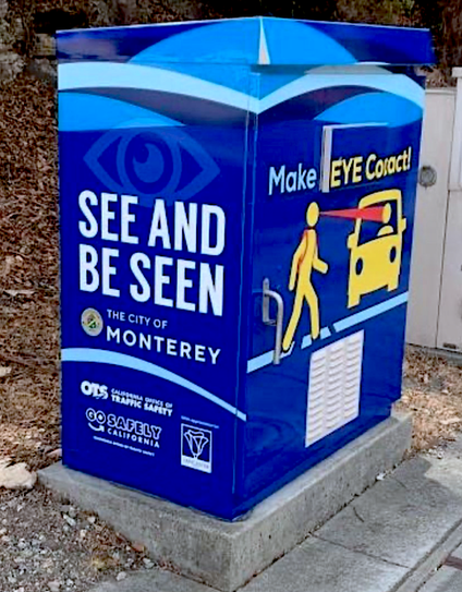 A blue cabinet wrap at a City of Monterey intersection shouts out “Make EYE Contact!” (if only we could!—often impossible).