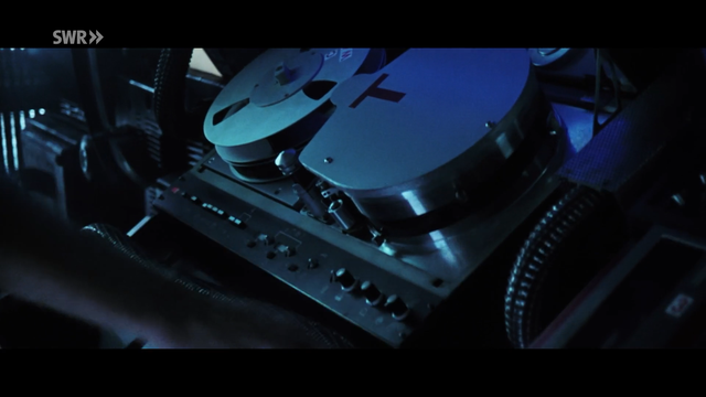 a very fancy looking polished metal tape drive as part of the space stations recording system in dim light