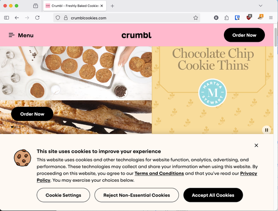 The image is a screenshot of the Crumbl Cookies website (crumbcookies.com) viewed in a web browser on a desktop computer.

At the top, the page header has a pink background with the Crumbl logo centered and a black “Order Now” button on the right. A hamburger-style “Menu” icon appears on the left.

Below the header, the main page features images of cookies. On the left, there’s a tray of freshly baked cookies with baking tools and ingredients (such as chocolate chips and brown sugar) surrounding it. On the right, there’s a yellow panel that reads “Chocolate Chip Cookie Thins” with a circular blue “Martha Stewart” logo underneath.

At the bottom of the screen is a cookie consent banner. It reads:

“This site uses cookies to improve your experience”
and explains that the site uses cookies for functionality, analytics, advertising, and performance. It provides options to:

Cookie Settings (button on the left)

Reject Non-Essential Cookies (center button)

Accept All Cookies (black button on the right)

The banner also includes a small cookie icon and links to the site’s Terms and Conditions and Privacy Policy.
