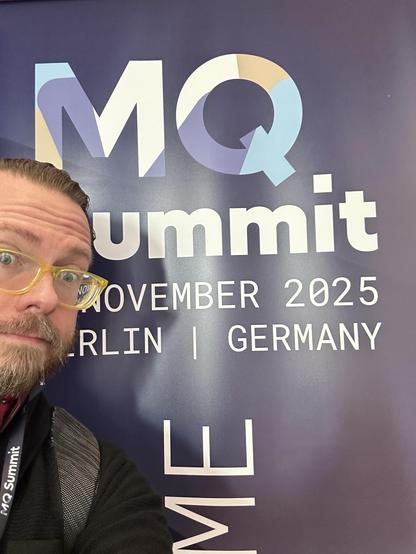 Me in front of a sign saying “MQ Summit”