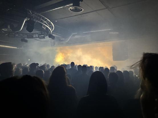 Mesmerized people looking at smoke from a lit stage