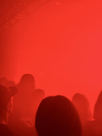 Smoke that is red with a few silhouettes of the audience