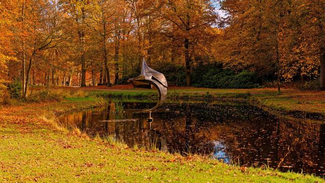 Art figure with autumn leaves on the trees and in the water, in a park.